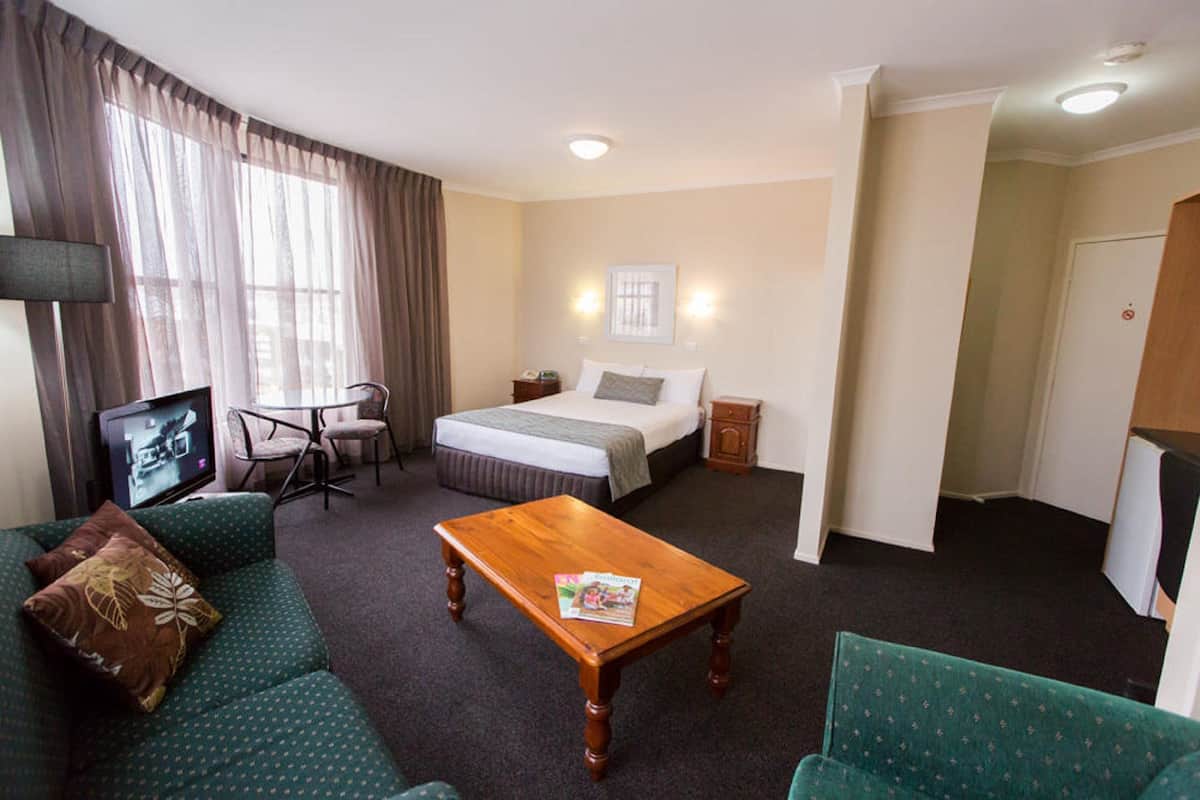 A hotel room with a bed, a sofa, a coffee table, a TV, and a desk.