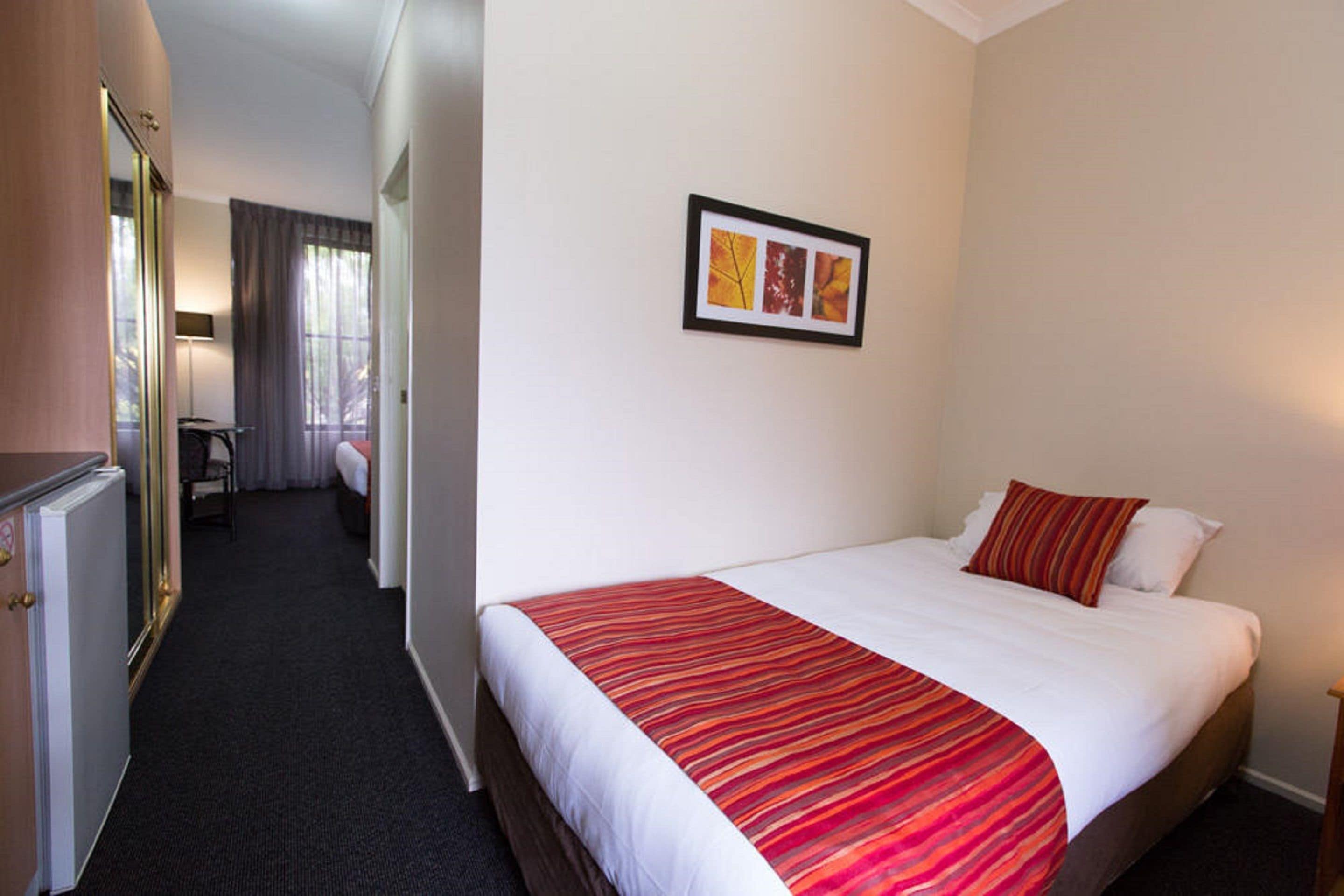 Habitación de hotel con una cama grande, un escritorio, una silla y un cuadro en la pared.