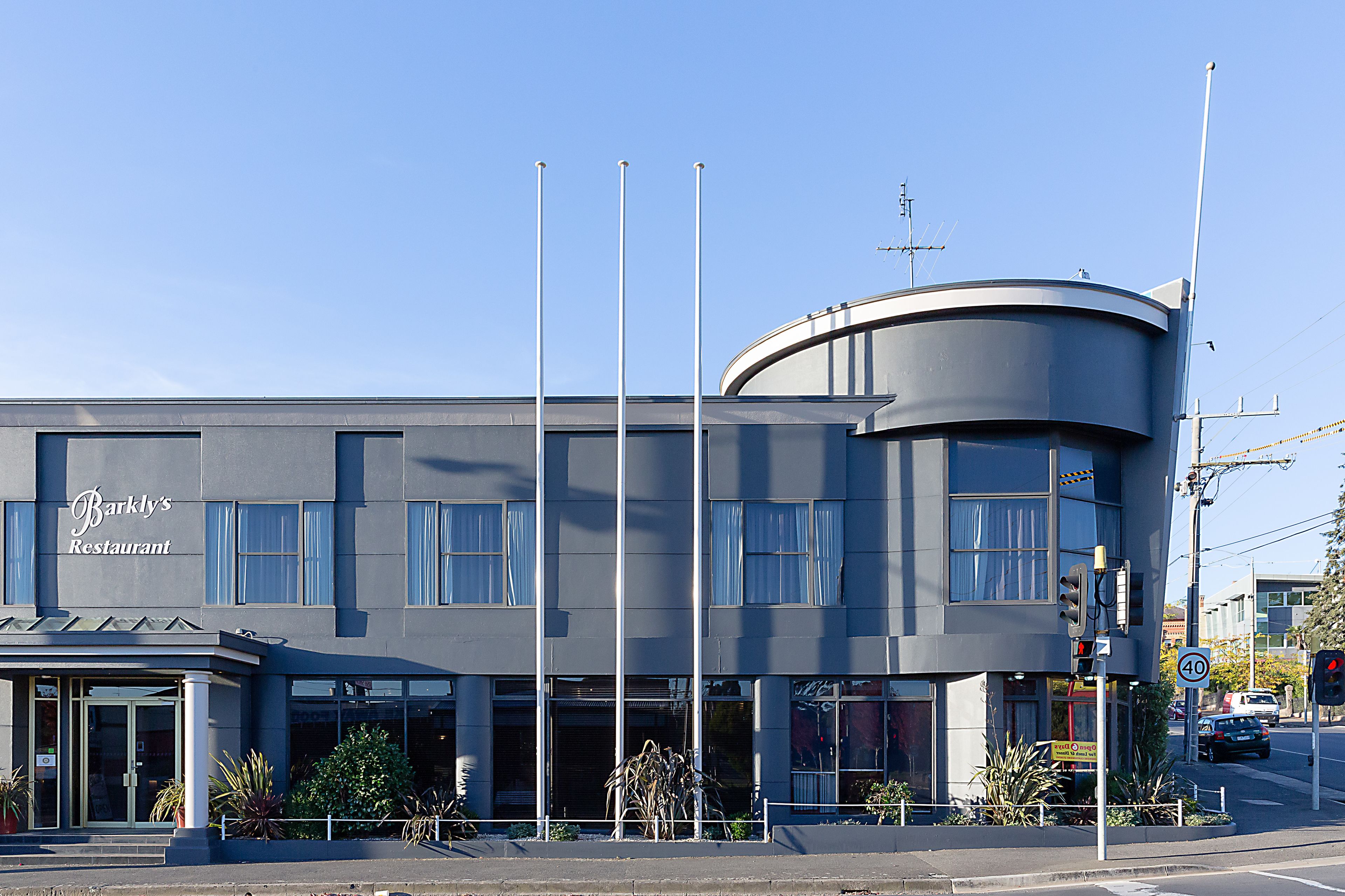 A modern building with a curved corner, a sign for Barkly's Restaurant, and a speed limit sign of 40.