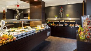 A buffet with various food items and a fruit display. - NH Danube City (Vienna)