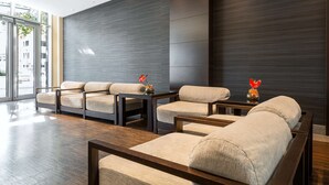 A modern lobby with a wooden floor, beige sofas, and dark walls. - NH Danube City (Vienna)