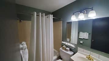 A bathroom with a shower curtain, toilet, sink, and mirror.