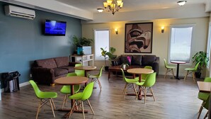 Una sala de estar moderna con un sofá marrón, sillas verdes, una mesa de centro de madera y un televisor en la pared.