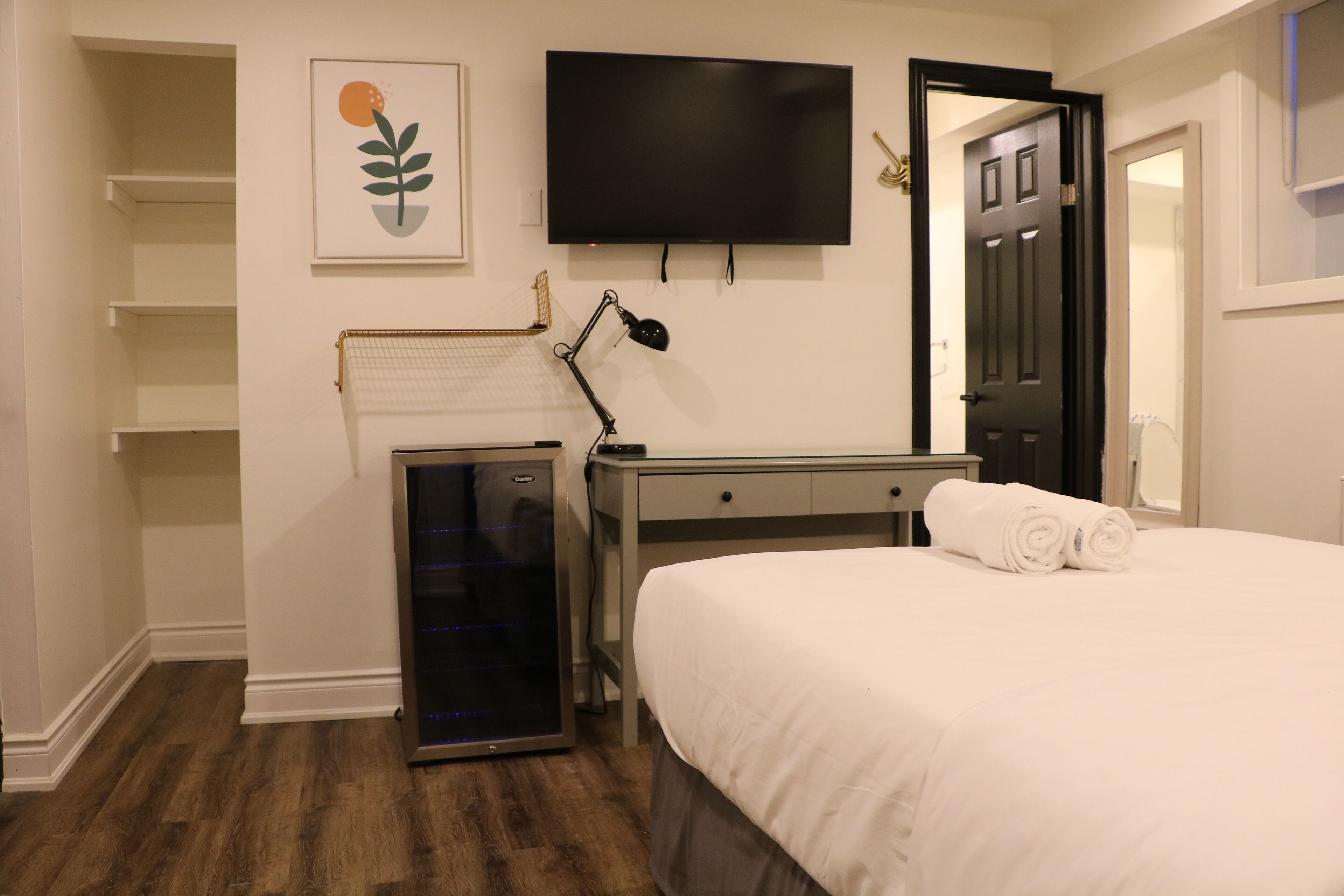 A hotel room with a bed, a desk, a TV, a heater, and a wardrobe.