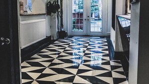A hallway with a black and white checkered floor, a large mirror, and a door leading to an outdoor area. - Pembroke Inn (Toronto)