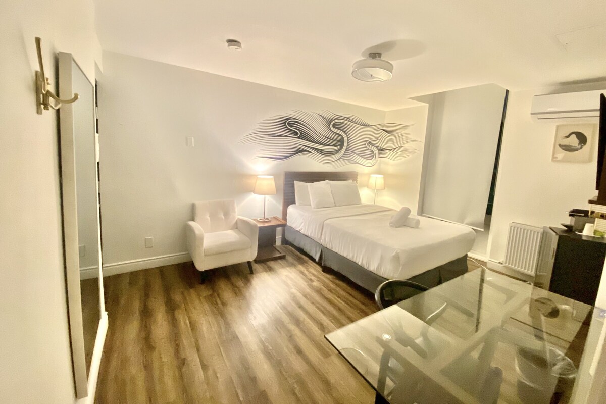 Una habitación de hotel con una cama, una silla, una mesita de vidrio y una pared con diseño decorativo.