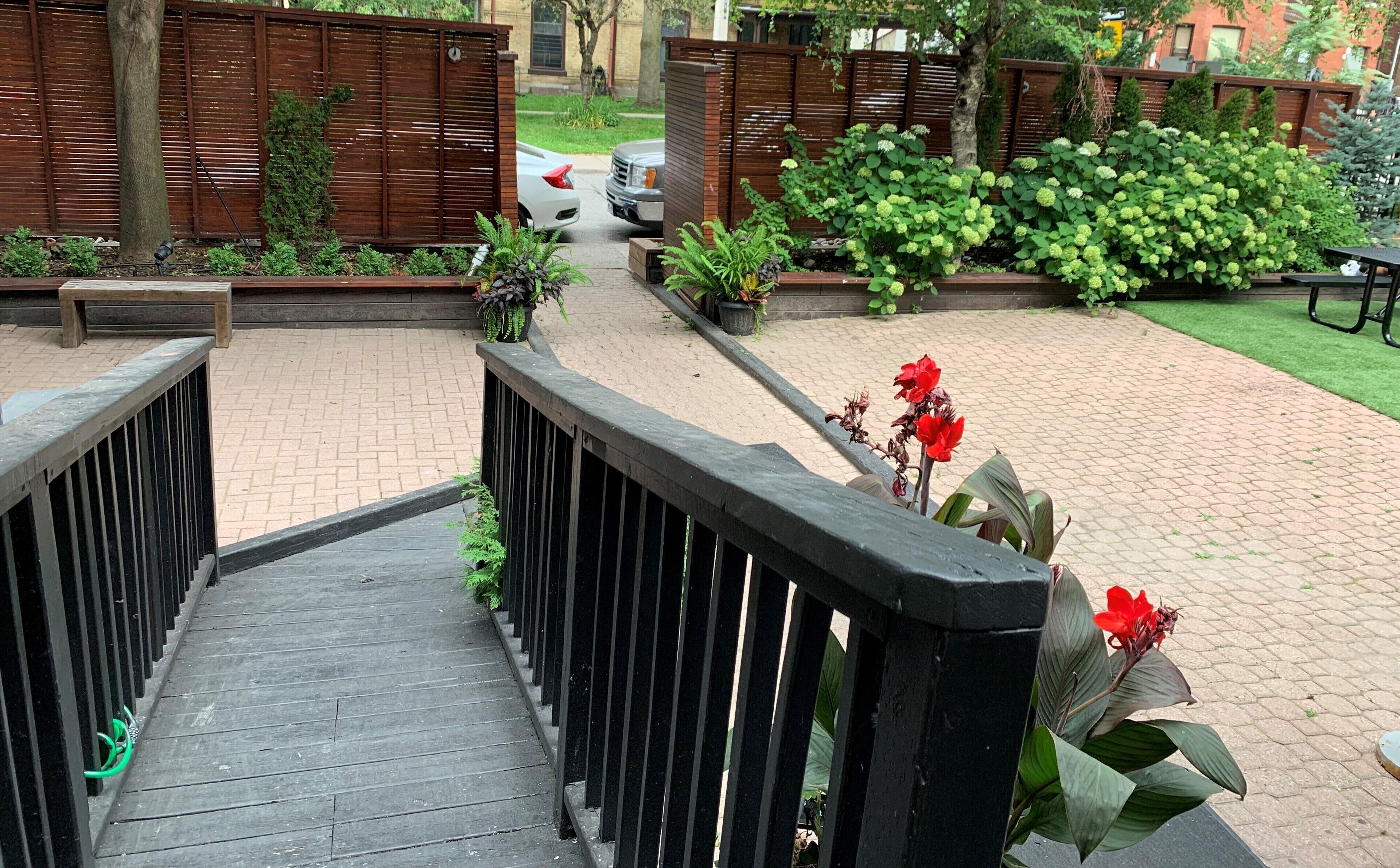 A wooden staircase leading to a covered area with a bench and potted plants.