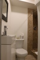 Een badkamer met toilet, wastafel, spiegel en douche.