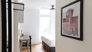 A bedroom with a bed, a window, and a framed picture on the wall. - Pembroke Inn (Toronto)