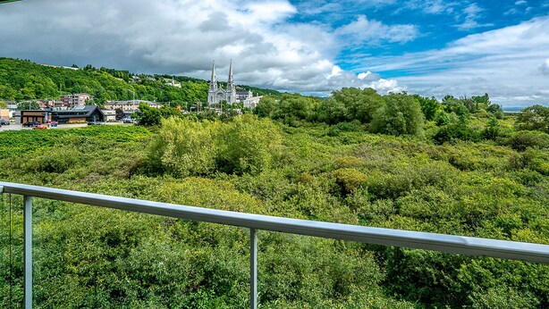 A view of a lush green landscape with a church and buildings in the distance. - Quality Suites (Ste Anne de Beaupre)