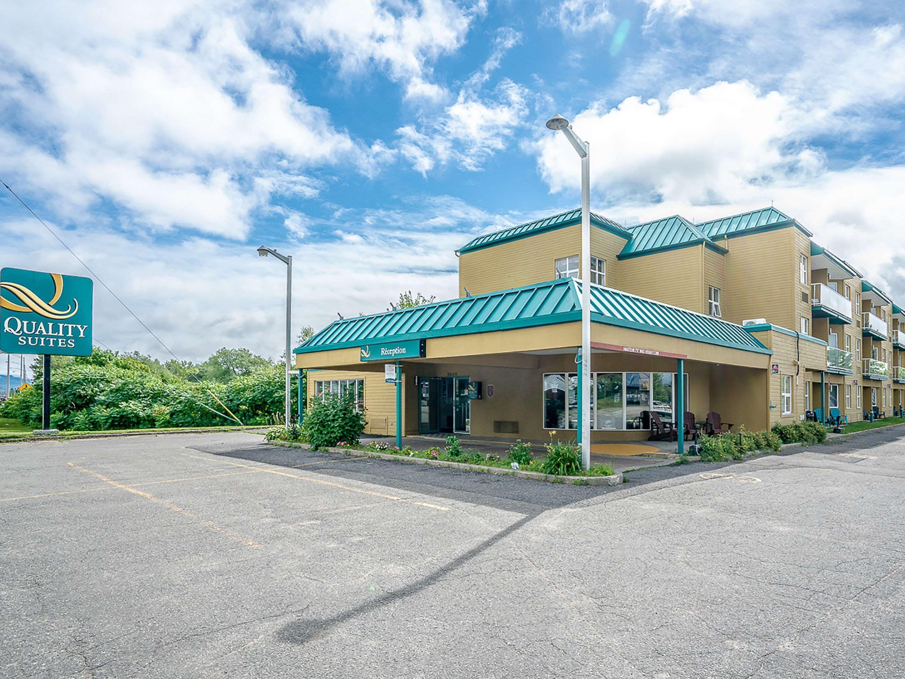 A hotel with a reception area, a parking lot, and a sign for Quality Suites.