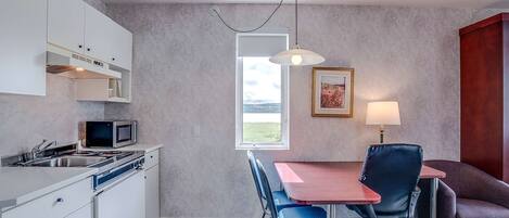 A compact kitchen with a dining area, including a table, chairs, and a view through the window.