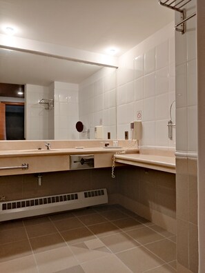 A modern bathroom with a large mirror, a sink with a towel rack, and a shower area.