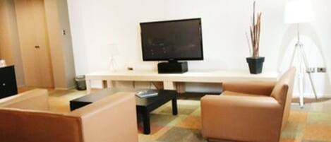 Una sala de estar moderna con un televisor de pantalla plana, dos sofás, una mesa de centro y una alfombra estampada.