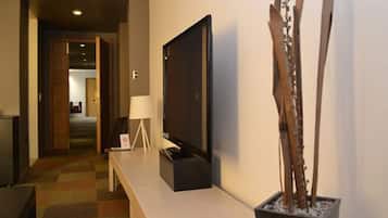 Un pasillo de hotel con un televisor de pantalla plana sobre un soporte, un banco y una escultura de madera decorativa.