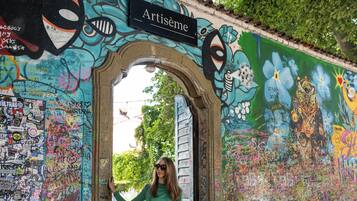 A woman in a green dress standing in front of a colorful graffiti-covered wall with a sign that reads "Artisienne."