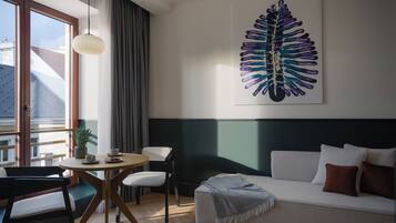 Een moderne kamer met een bank, een eettafel en een groot abstract kunstwerk aan de muur.
