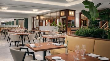 Ein modernes Restaurant mit mehreren Tischen, Stühlen und einer zentralen Sitzgruppe mit gepolsterten Bänken.