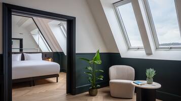 A modern bedroom with a bed, a potted plant, a chair, and a small table.