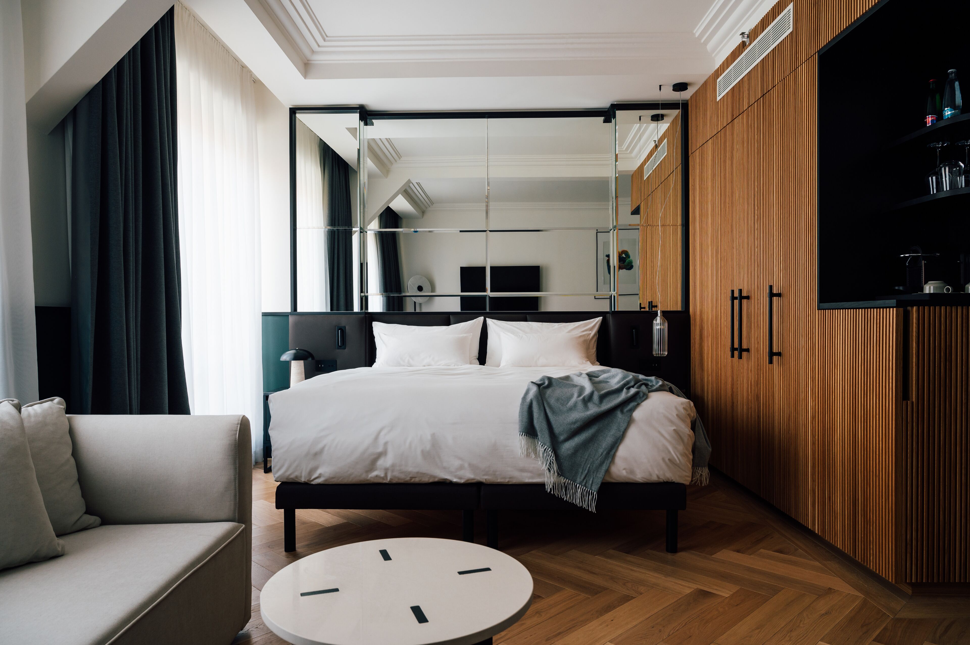 Une chambre d’hôtel moderne avec un grand lit, un canapé, une table ronde et une armoire.