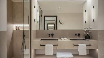A modern bathroom with two sinks, a large mirror, and a glass-enclosed shower.
