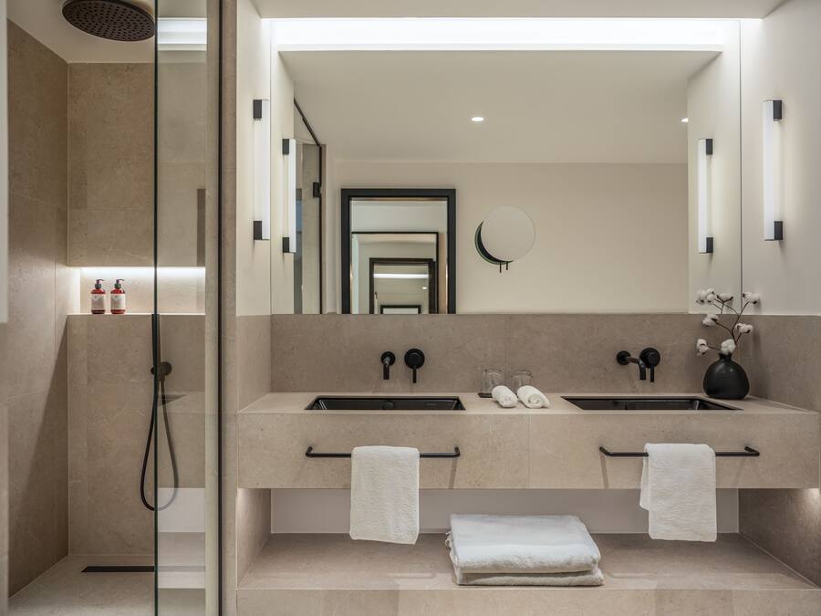 A modern bathroom with two sinks, a large mirror, and a glass-enclosed shower.