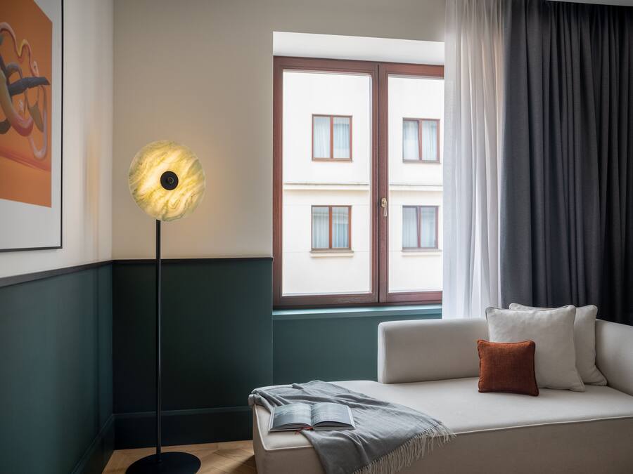 Una sala moderna con sofá, lámpara de pie y ventana con cortinas.