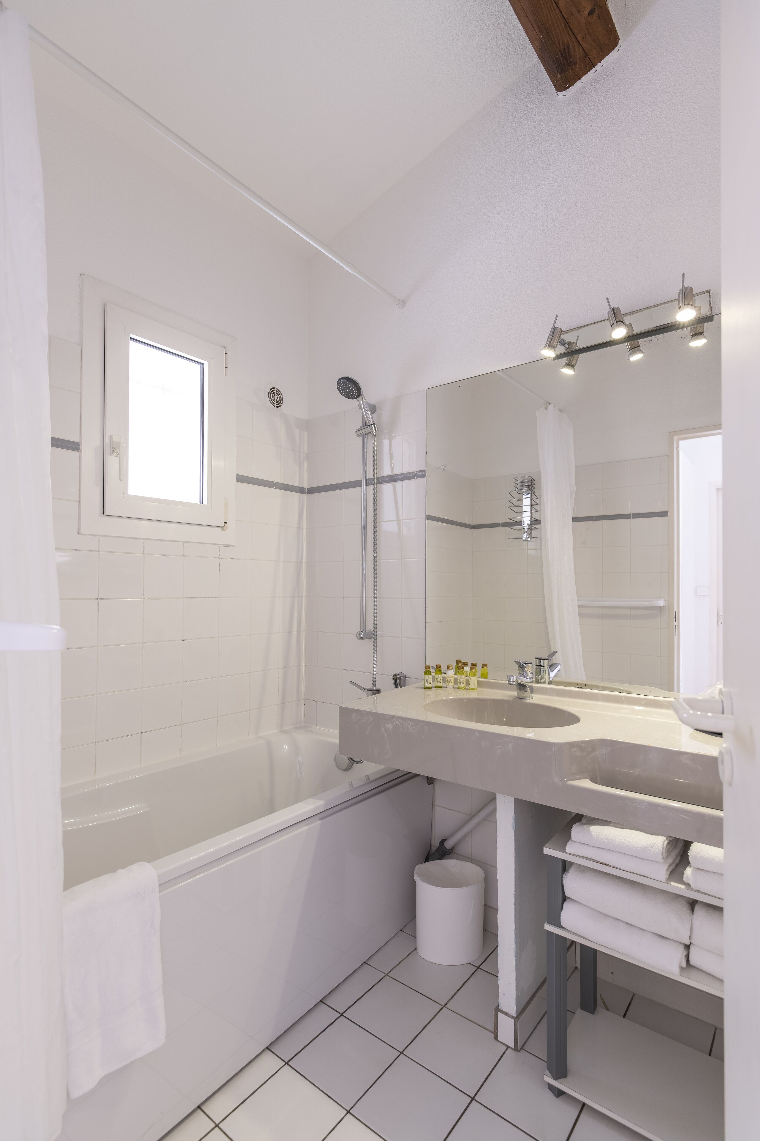 A modern bathroom with a bathtub, a large mirror, and a vanity with a sink.