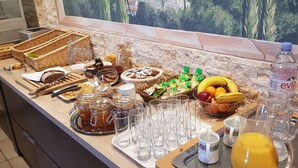 Un bufé de desayuno con diversas opciones de comida, incluyendo frutas, pan y bebidas.