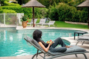 Una piscina al aire libre de temporada, sombrillas, tumbonas