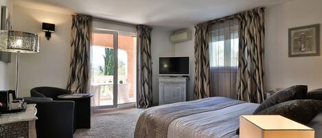 A hotel room with a bed, a desk, a chair, a TV, and a view of the outdoors.