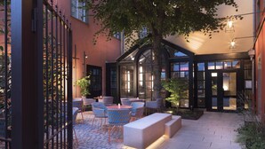 An outdoor patio with tables and chairs, a stone bench, and a tree providing shade. - Hotel Du Dragon (Strasbourg)