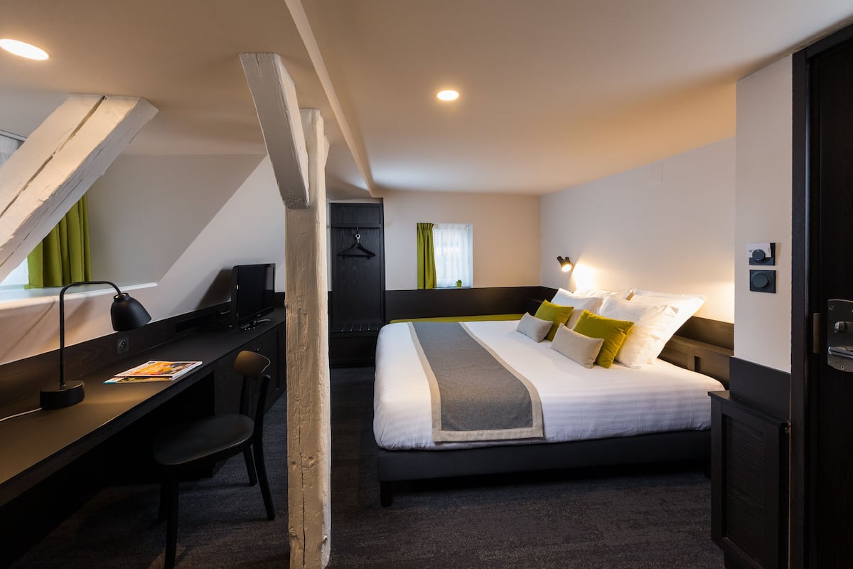 A modern hotel room with a bed, desk, and chair.