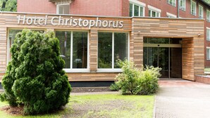 Et hotel kaldet "Hotel Christophorus" med en moderne facade, store vinduer og en velholdt have.