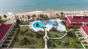 Ein Resort mit zentralem Pool, Zugang zum Strand und einem Gebäude mit rotem Dach.