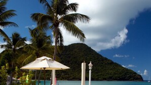 Eine Strandlounge mit Liegestühlen, einem Tisch mit Korb und einer Lampe.
