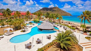 Ein Resort mit einem zentralen Pool, Strandliegen und Bergblick.