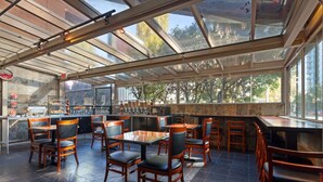 Ein Restaurant mit Glasdecke, Holztischen und -stühlen sowie einer Steinwand.