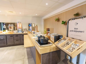 A breakfast buffet area with a sign reading 'Bon petit déjeuner!' and a coffee machine. - ibis Laon (Laon)