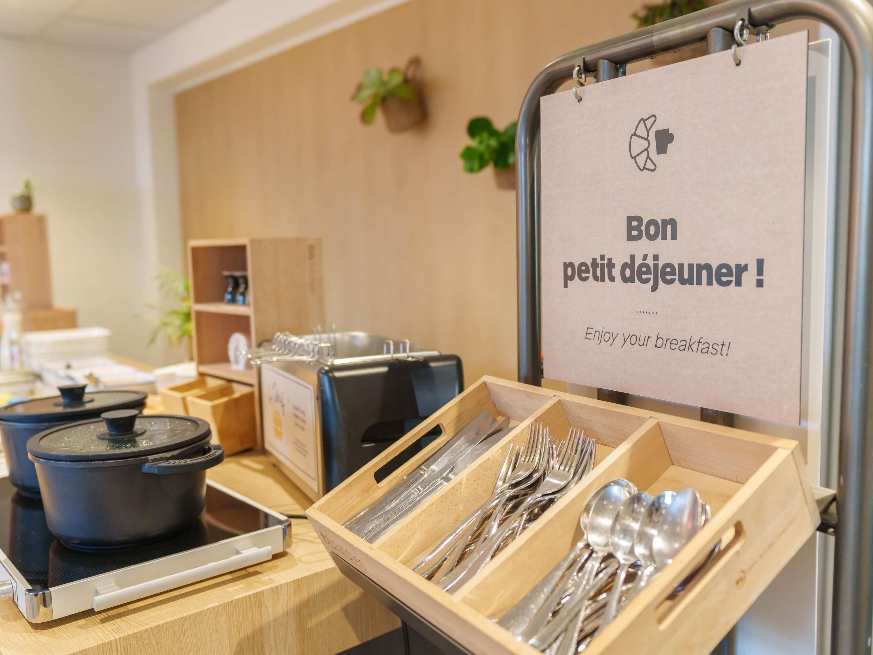Aamiaispöytä, jossa on kyltti, jossa lukee: ”Hyvää aamupalaa!” ja ruokailuvälineet puulaatikossa.