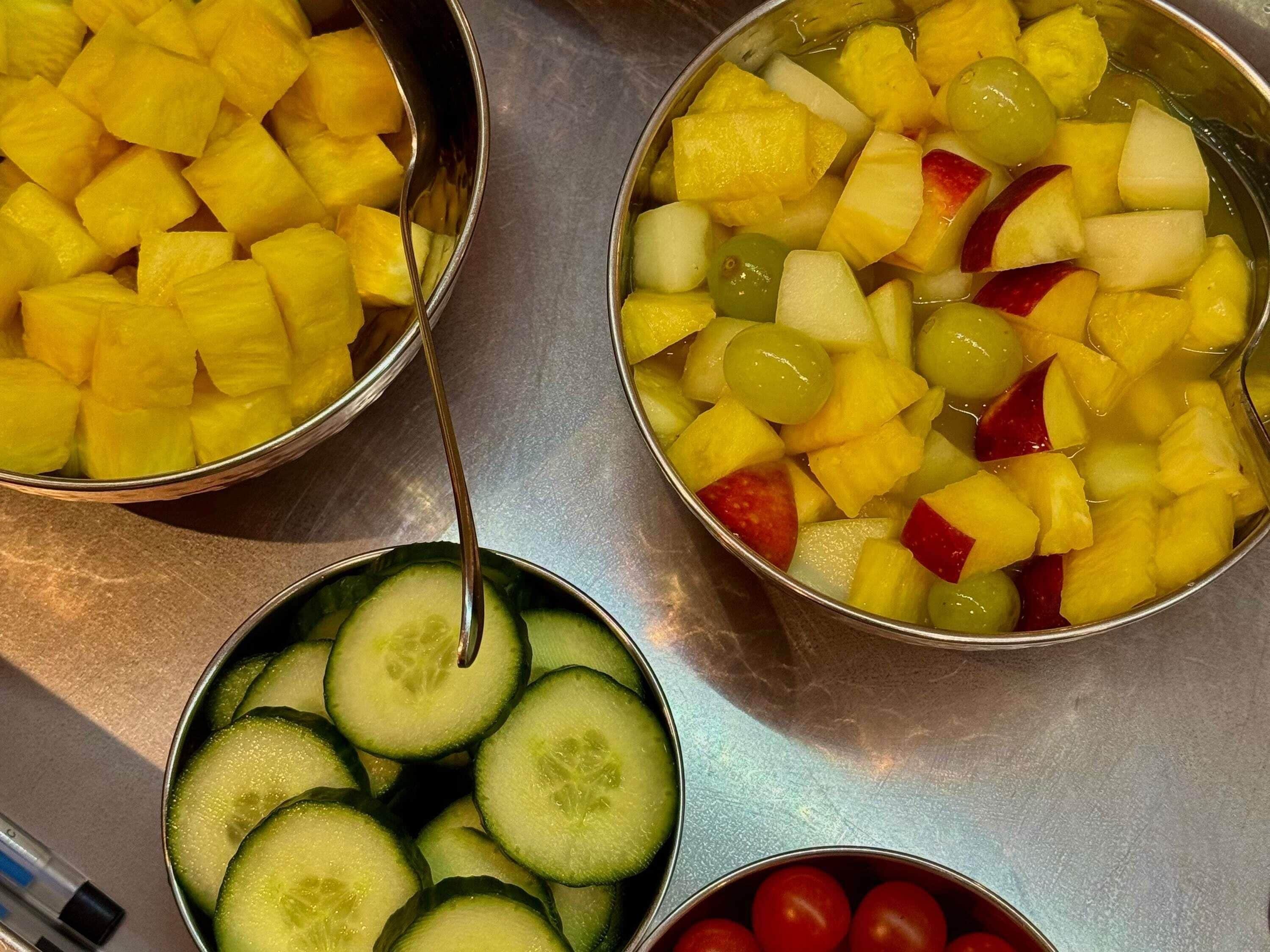 Three metal bowls containing diced fruits and vegetables.