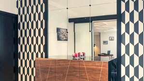 Un interior moderno con paredes de diseño geométrico, un mueble de madera y una partición de vidrio.