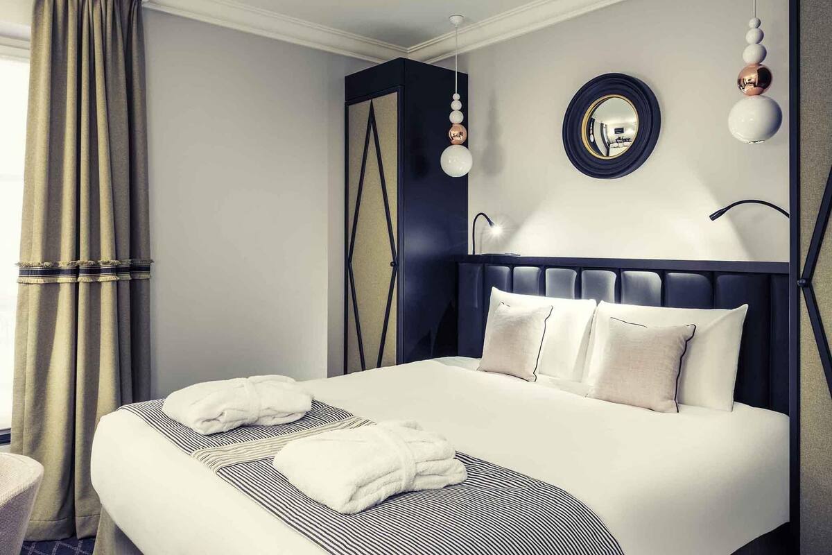 Una habitación de hotel moderna con una cama grande, un espejo redondo y un elemento decorativo en la pared.