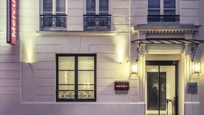Fachada de hotel con un llamativo letrero 'Mercure', amplias ventanas y una entrada bien iluminada.