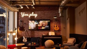 A cozy lounge area with a brick wall, a neon sign reading "You play", a television, a piano, and comfortable seating. - Inter-hotel Deauville Gare Continental (Deauville)