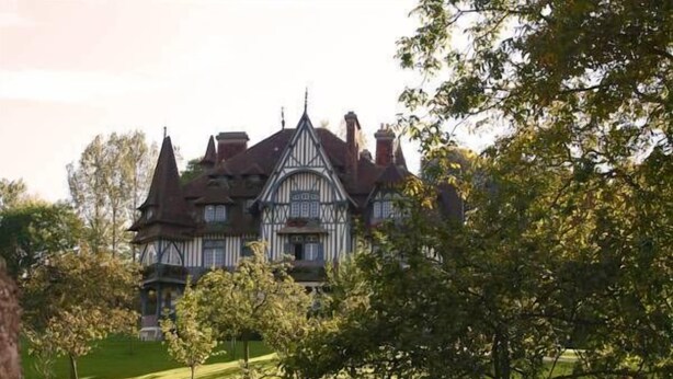 A large, historic building with multiple towers and a prominent central entrance, surrounded by a well-maintained lawn and trees. - Inter-hotel Deauville Gare Continental (Deauville)