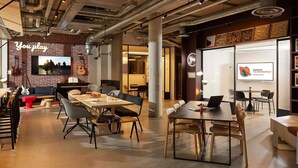 A modern office space with exposed ceilings, a brick wall with a TV, and a piano. - Inter-hotel Deauville Gare Continental (Deauville)