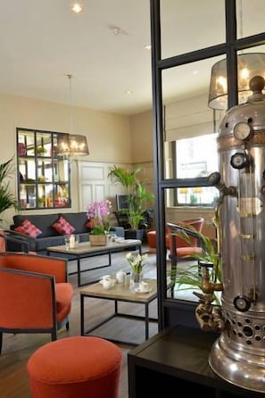 A modern living room with a large window, a decorative metal stove, and a seating area with a sofa and armchairs.