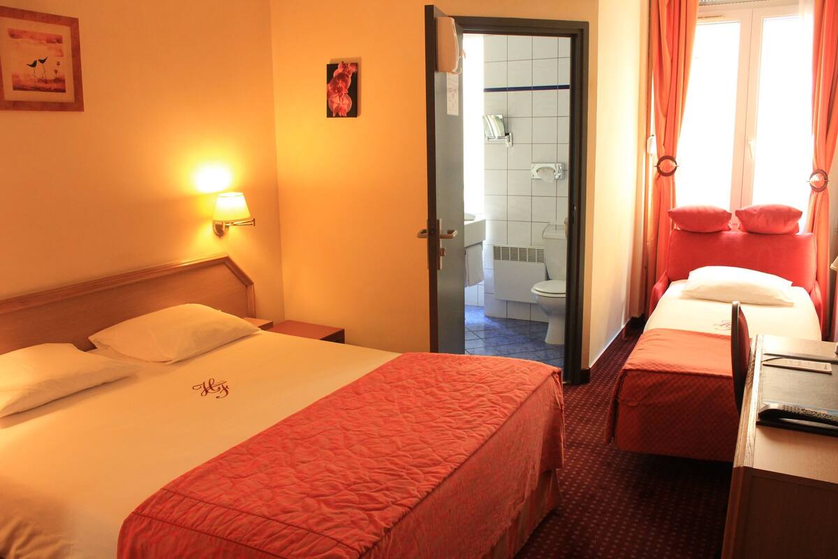 A hotel room with a bed, a desk, and a bathroom visible through an open door.