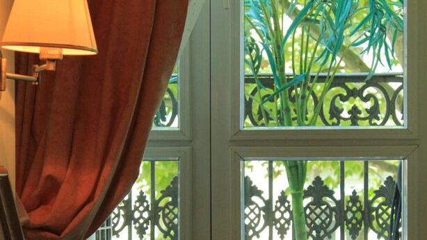 Ein Schlafzimmer mit einem Bett, einer Lampe und einem Fenster mit Blick auf Grünflächen.